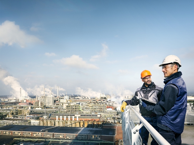 Two engineers look at a large industrial plant.