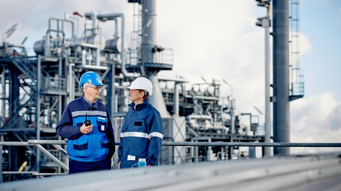 Technical experts in front of a refinery