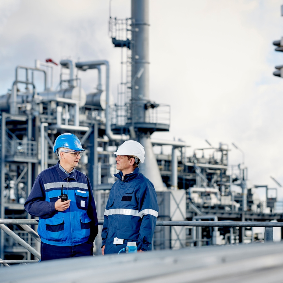 Technical experts in front of a refinery