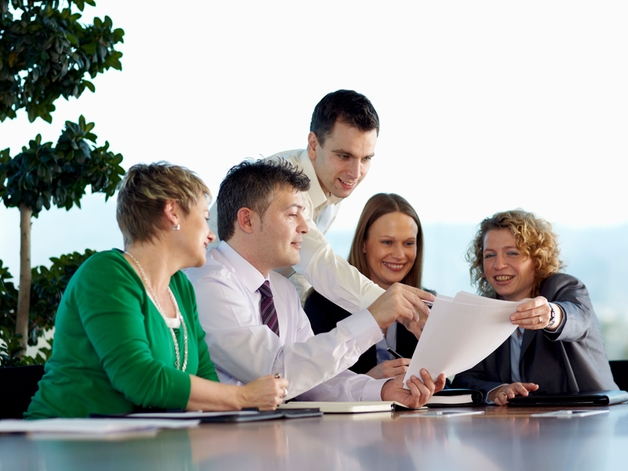 Group of employees discussion at a large meeting table.