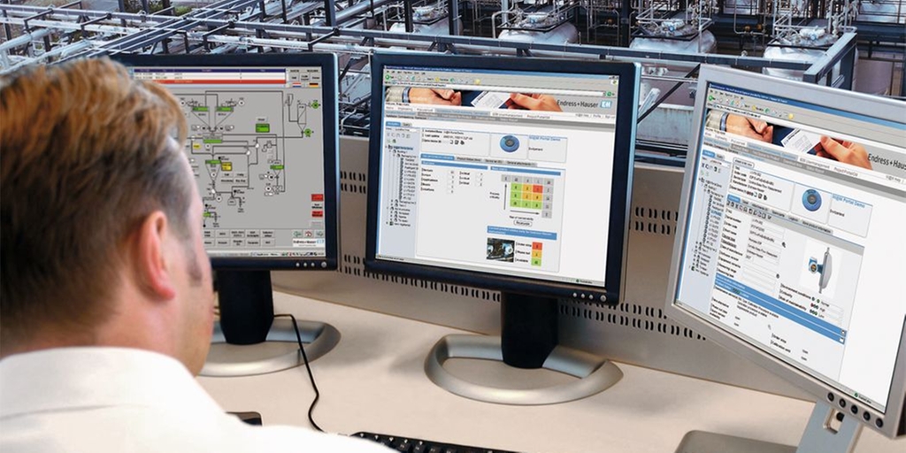 Flowmeter calibration data stored in an asset management system (W@M Life Cycle Management System) Man sitting in front of a computer overlooking plant getting informtion from asstes on the screen