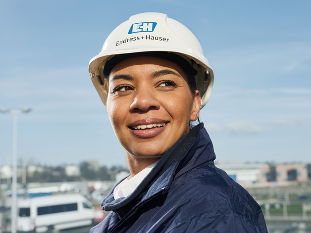 Female engineer with white helmet in front of blue sky.